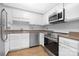 Well-lit kitchen with white cabinets, laminate floors, stainless steel appliances, and stainless steel sink at 10101 Wood Ct, Charlotte, NC 28277