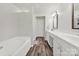 Bright bathroom featuring a soaking tub and double sink vanity with white cabinets and modern fixtures at 10135 Blakeney Preserve Dr, Charlotte, NC 28277