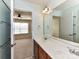 Bright bathroom featuring double vanity, large mirror and an open doorway to the carpeted bedroom at 1016 Yellow Daisy Dr, Matthews, NC 28104