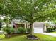 Beautifully landscaped front yard with mature trees and green grass complementing the brick facade of the home at 1016 Yellow Daisy Dr, Matthews, NC 28104