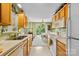 Galley kitchen offers wooden cabinets, white appliances, and a view into the dining area at 10621 Glenmac Rd, Charlotte, NC 28215