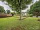 Lush backyard showcasing mature trees, a wooden deck, and a charming picnic spot at 116 Birchwood Ct, Mount Holly, NC 28120