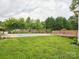 View of backyard pool with deck, grass and a privacy fence of lush trees at 116 Birchwood Ct, Mount Holly, NC 28120