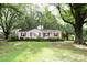 Quaint single-story home with red shutters surrounded by large, mature trees, creating a peaceful setting at 1270 N Enochville Ave, China Grove, NC 28023