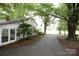 Back view of a home with an enclosed sunroom surrounded by mature trees and a long driveway at 1270 N Enochville Ave, China Grove, NC 28023