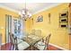 Stylish dining room with a glass-top table, elegant chandelier, and vibrant walls at 14018 Drake Watch Ln, Charlotte, NC 28262