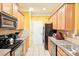 Bright eat-in kitchen has wood cabinets, black appliances, and tile floors at 14018 Drake Watch Ln, Charlotte, NC 28262