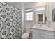 Bright bathroom with vanity, toilet, and a shower featuring a patterned curtain and natural light at 151 Outrigger Ln, Troutman, NC 28166