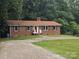 Charming brick home with black shutters and a red door, complemented by a gravel driveway and green lawn at 1660 Songwood Rd, Concord, NC 28025