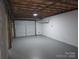 Unfinished basement garage with an open ceiling and painted concrete block walls and floor at 1660 Songwood Rd, Concord, NC 28025