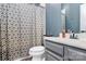 Bathroom with white sink, vanity with grey cabinets, and shower with patterned curtain at 1723 Town Oak Ln, Charlotte, NC 28205