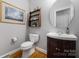 A half bathroom featuring a sleek vanity with a round mirror and a decorative shelf and picture frame at 188 Lilac Mist Loop, Mooresville, NC 28115