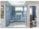A frameless glass shower boasts blue subway tiles, a rainfall showerhead, and a built in bench at 188 Lilac Mist Loop, Mooresville, NC 28115