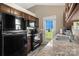 Galley style kitchen with black appliances, granite countertops, tile backsplash, and access to outdoor patio at 209 Mcfadden St, Rock Hill, SC 29730