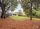 Backyard view with a covered porch on a grassy lot lined with trees and mulch at 2421 Morton St, Charlotte, NC 28208