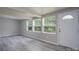 Basement living area with gray walls, three windows, gray wood-look floors, and a white door at 2617 Shady Lane Ave, Concord, NC 28027