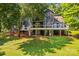 A backyard view of a two-story house featuring a deck, patio, and lush green grass at 315 Wood Duck Loop, Mooresville, NC 28117