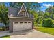 A modern garage exterior featuring an upstairs loft, an oversized garage door, and lush landscaping at 315 Wood Duck Loop, Mooresville, NC 28117