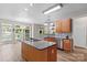 An open kitchen features granite counters, wood cabinets, backsplash, cooktop island, recessed lighting, and wood floors at 315 Wood Duck Loop, Mooresville, NC 28117