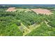 Aerial view showcasing a home nestled within a lush, tree-filled landscape near open fields at 320 Bluegill Ln, Statesville, NC 28625