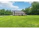 Lovely backyard featuring lush green lawn, mature trees, outbuilding, and deck at 320 Bluegill Ln, Statesville, NC 28625