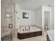 Bright bathroom featuring a soaking tub with dark fixtures and a glass-enclosed shower at 4644 Snow Dr, Harrisburg, NC 28075