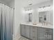 Bright bathroom featuring dual sinks, modern fixtures, framed mirrors, and stylish vanity at 4644 Snow Dr, Harrisburg, NC 28075