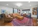 Bright living room showcasing a red patterned rug, tan sofa, and a modern wooden coffee table at 4644 Snow Dr, Harrisburg, NC 28075