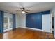 Bedroom with wooden floors, blue accent wall, window with blinds, and a ceiling fan at 4672 Snow Dr, Harrisburg, NC 28075