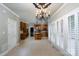 Open sunroom with tiled floors, chandelier, and view to the wooden cabinet kitchen with granite countertops at 4672 Snow Dr, Harrisburg, NC 28075