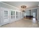 Bright sunroom with tiled floors, a modern chandelier, and many large windows with shutters at 4672 Snow Dr, Harrisburg, NC 28075