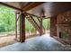 Relaxing covered patio overlooking a lush backyard with a brick fireplace and stairs at 4672 Snow Dr, Harrisburg, NC 28075