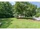 Large, grassy backyard with mature trees and a storage shed at 5424 Doncaster Dr, Charlotte, NC 28211
