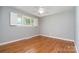 Empty bedroom featuring wood floors, a ceiling fan, and a double-hung window with shutters at 5424 Doncaster Dr, Charlotte, NC 28211