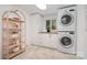 Bright laundry room features a stacked washer and dryer, wood shelves and storage at 5424 Doncaster Dr, Charlotte, NC 28211