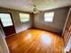 Bright bedroom featuring hardwood floors, neutral walls, a ceiling fan, and natural light from two windows at 6229 Mountain Grove Rd, Hickory, NC 28602