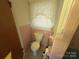Small bathroom with a standard toilet and matching tile and a partially open door at 6229 Mountain Grove Rd, Hickory, NC 28602