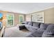 Cozy living room with neutral colors, a plush gray sectional, and abundant natural light from the windows at 7528 Red Oak Ln, Charlotte, NC 28226