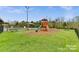 Outdoor wooden playground with a slide and swingset features a natural wooded backdrop at 8109 Hawk Crest Ct, Charlotte, NC 28270