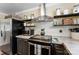 Compact kitchen featuring subway tile backsplash, stainless appliances, and open shelving for storage at 110 Heritage Dr, Kings Mountain, NC 28086
