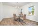 Open dining room with wood floors, modern chandelier, and a glass table with seating for six at 11116 Godwit Ln, Charlotte, NC 28278
