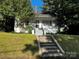 Charming home featuring a covered porch, brick chimney, and landscaped front yard at 208 S Ransom St, Gastonia, NC 28052