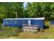 Exterior view of blue mobile home with a white porch and green lawn at 41042 Dennis Rd, Albemarle, NC 28001