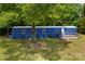 A mobile home with a blue exterior and a small porch surrounded by lush greenery and trees at 41042 Dennis Rd, Albemarle, NC 28001
