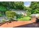 Charming backyard with brick patio, stainless grill, and a storage building surrounded by flowering bushes at 4200 Tyndale Ave, Charlotte, NC 28210