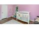 Pink Bedroom with hardwood floor, crib, storage, and natural light at 4200 Tyndale Ave, Charlotte, NC 28210