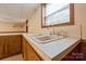 Close up of basement double sink featuring a goose-neck faucet and Formica countertop with wood cabinets at 46 Donna Dale Se Ave, Concord, NC 28025