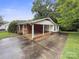 Ranch-style home featuring a covered porch with brick accents, a concrete driveway, and mature trees at 46 Donna Dale Se Ave, Concord, NC 28025