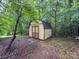 An outdoor shed with a barn roof design sits among the trees in the backyard at 46 Donna Dale Se Ave, Concord, NC 28025