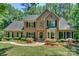 Traditional brick home featuring a manicured lawn, mature trees, and classic black shutters at 5485 Deer Run Ct, Davidson, NC 28036